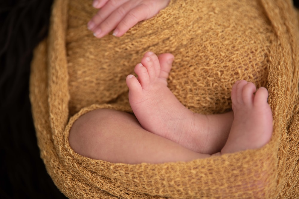 baby lying on brown textile