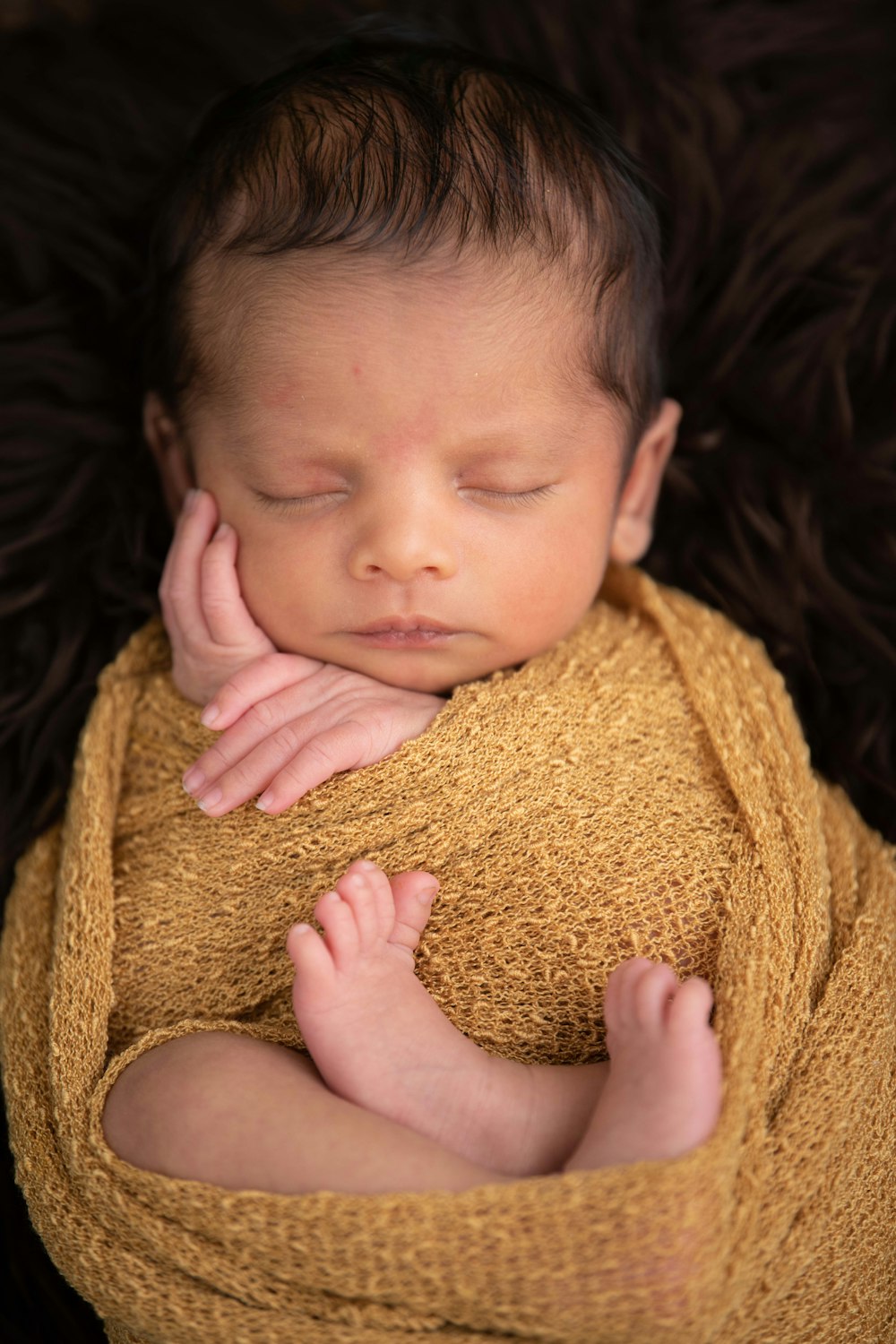 child covered with brown blanket