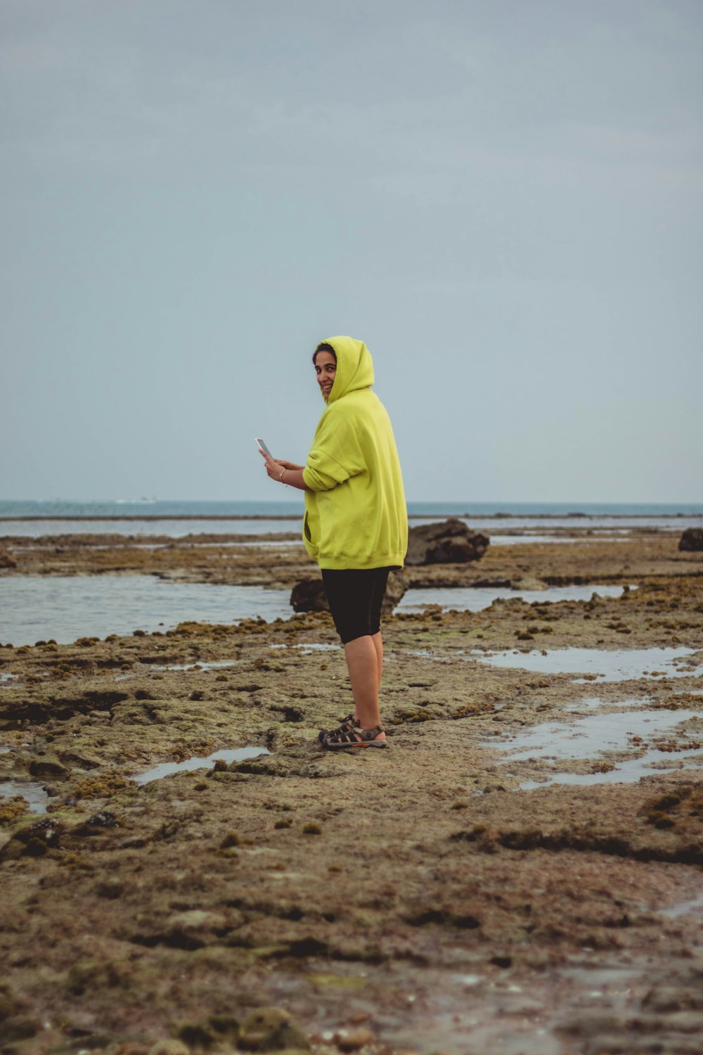 man in yellow hoodie standing on beach during daytime