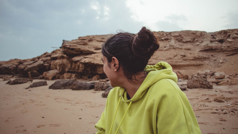 man in green hoodie standing on beach during daytime