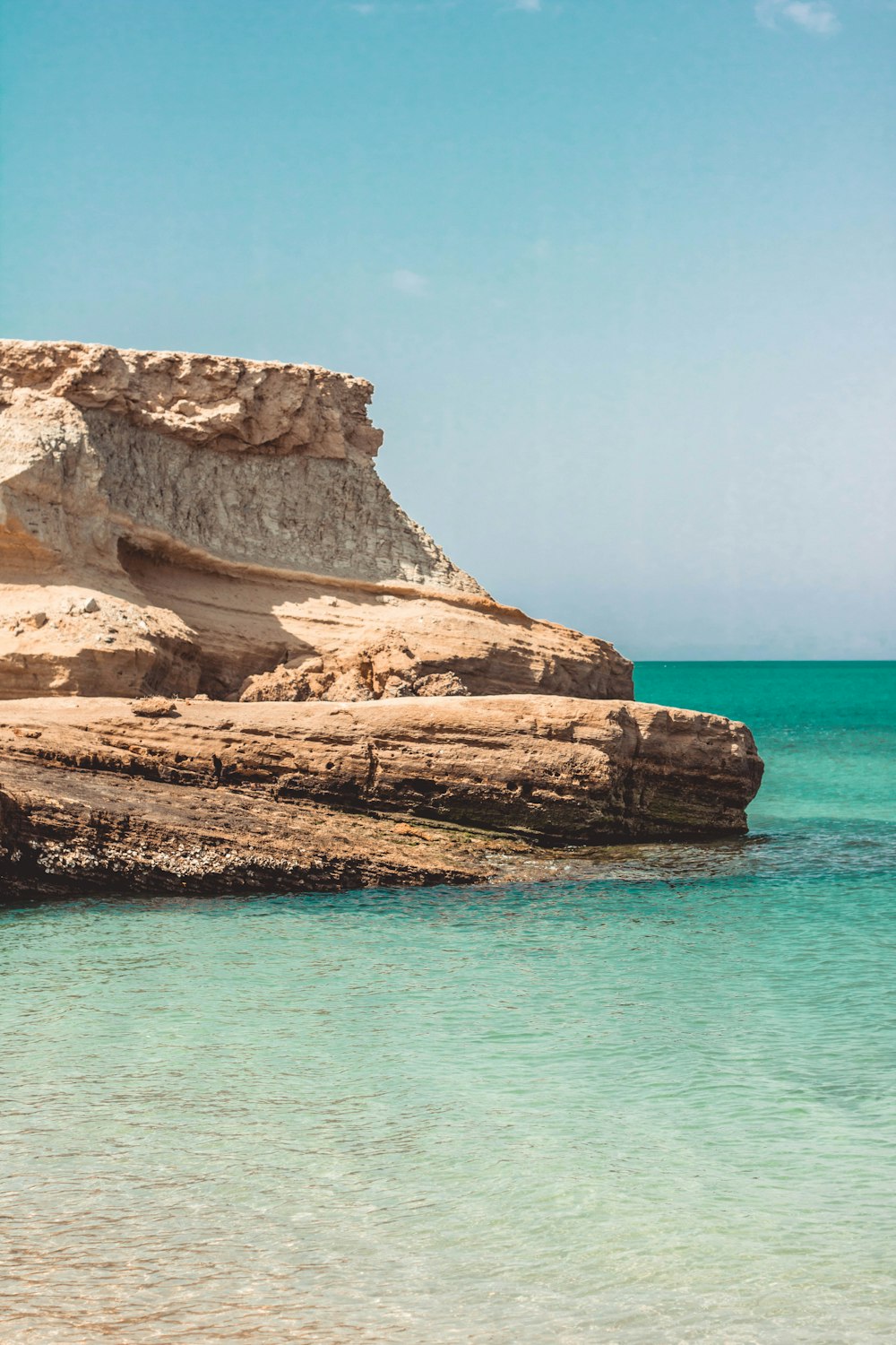 brown rock formation on blue sea under blue sky during daytime