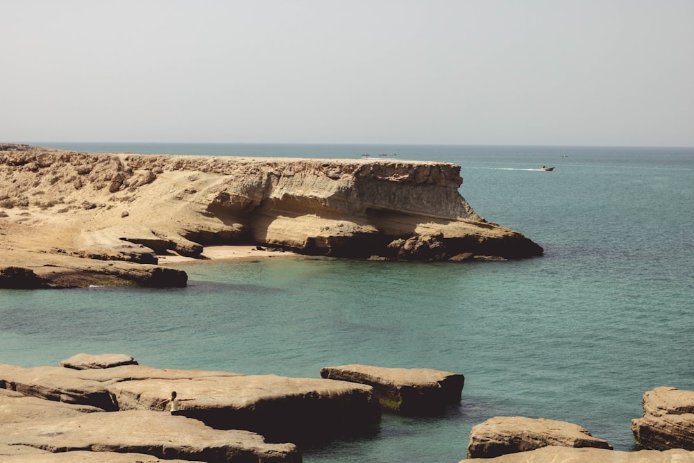 brown rocky mountain beside sea during daytime