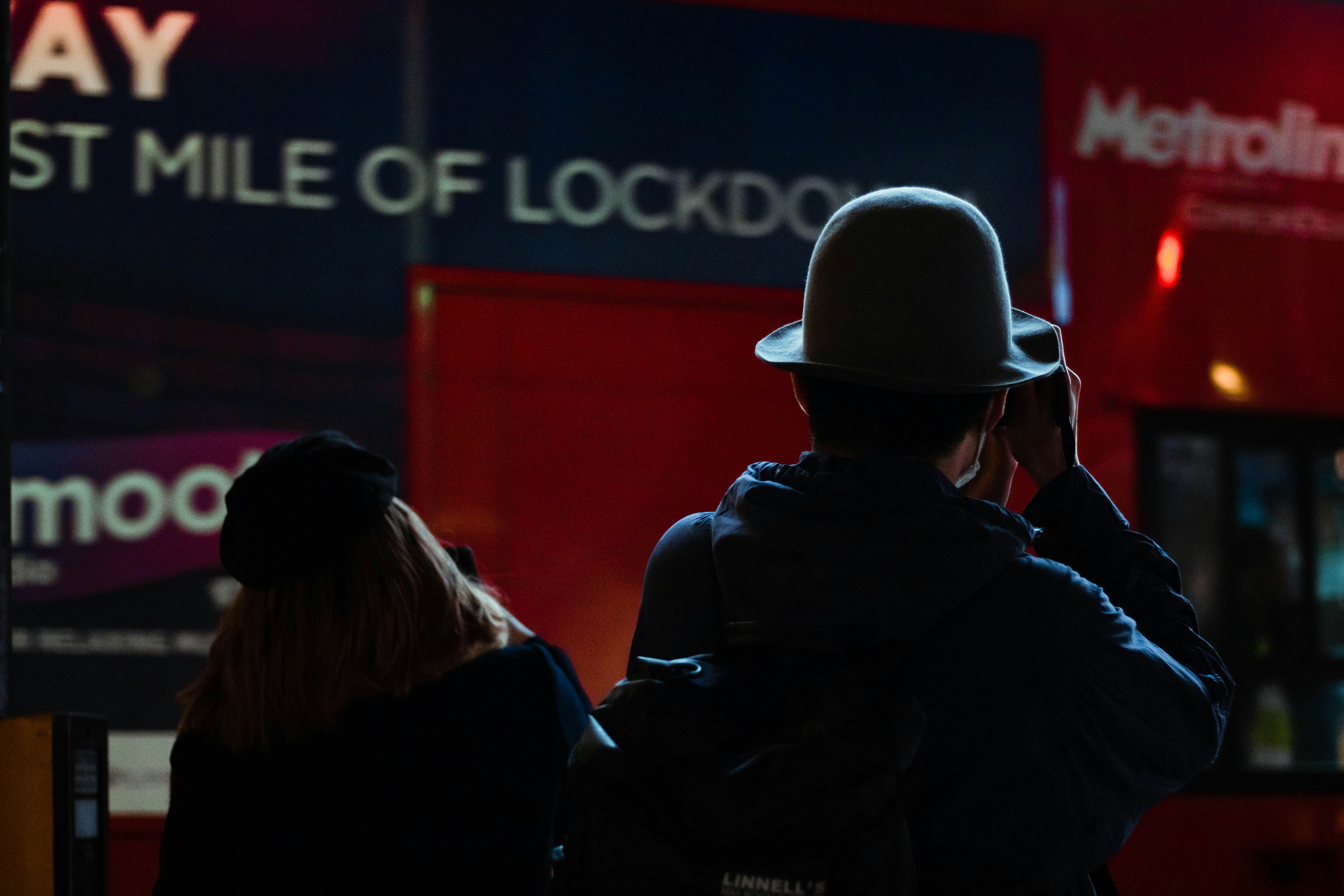 man and woman in black jacket standing in front of red wall