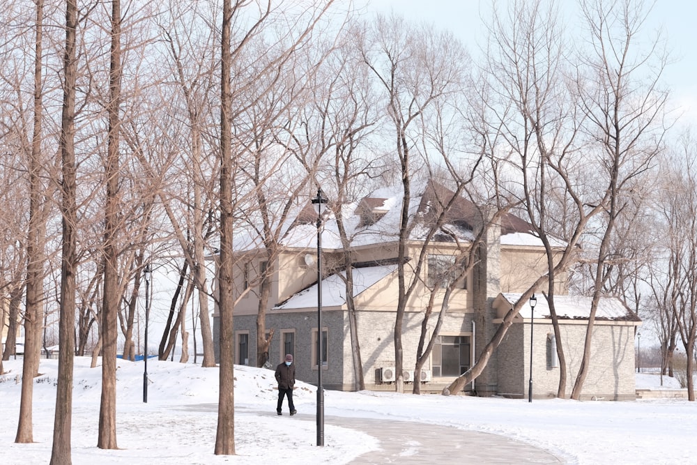 person in black jacket walking on snow covered ground near bare trees during daytime