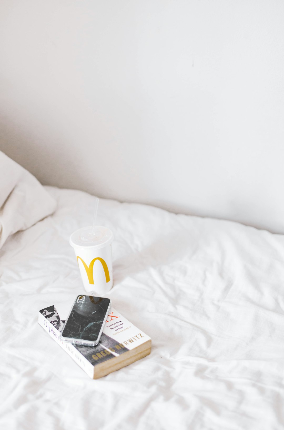 white ceramic mug on white book on white bed