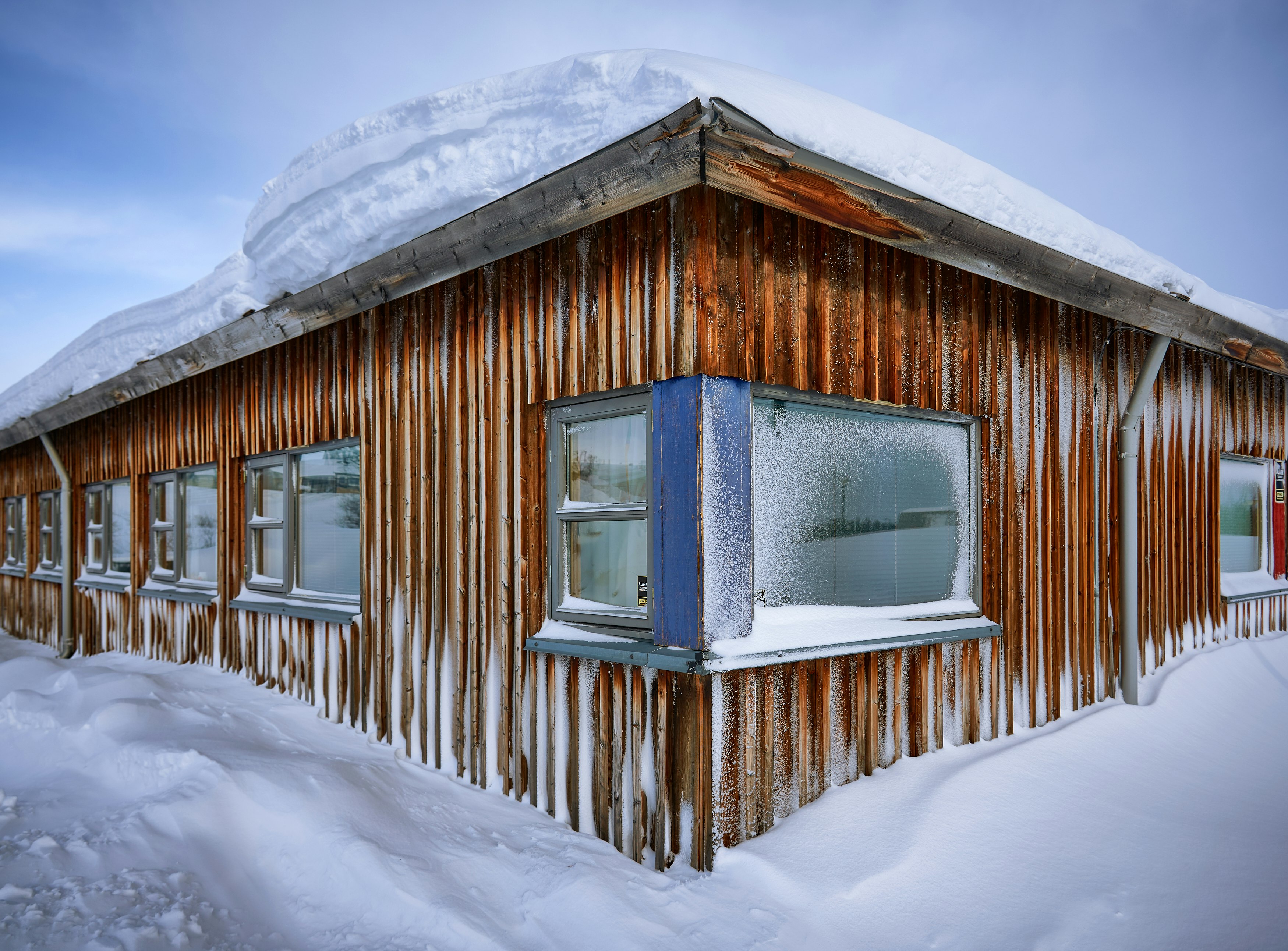 brown wooden house covered with snow during daytime