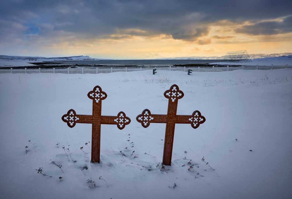 brown wooden cross on snow covered ground during daytime