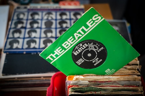 A vintage microphone beside a stack of classic Beatles vinyl records.