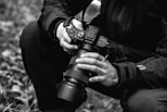 grayscale photo of person holding dslr camera