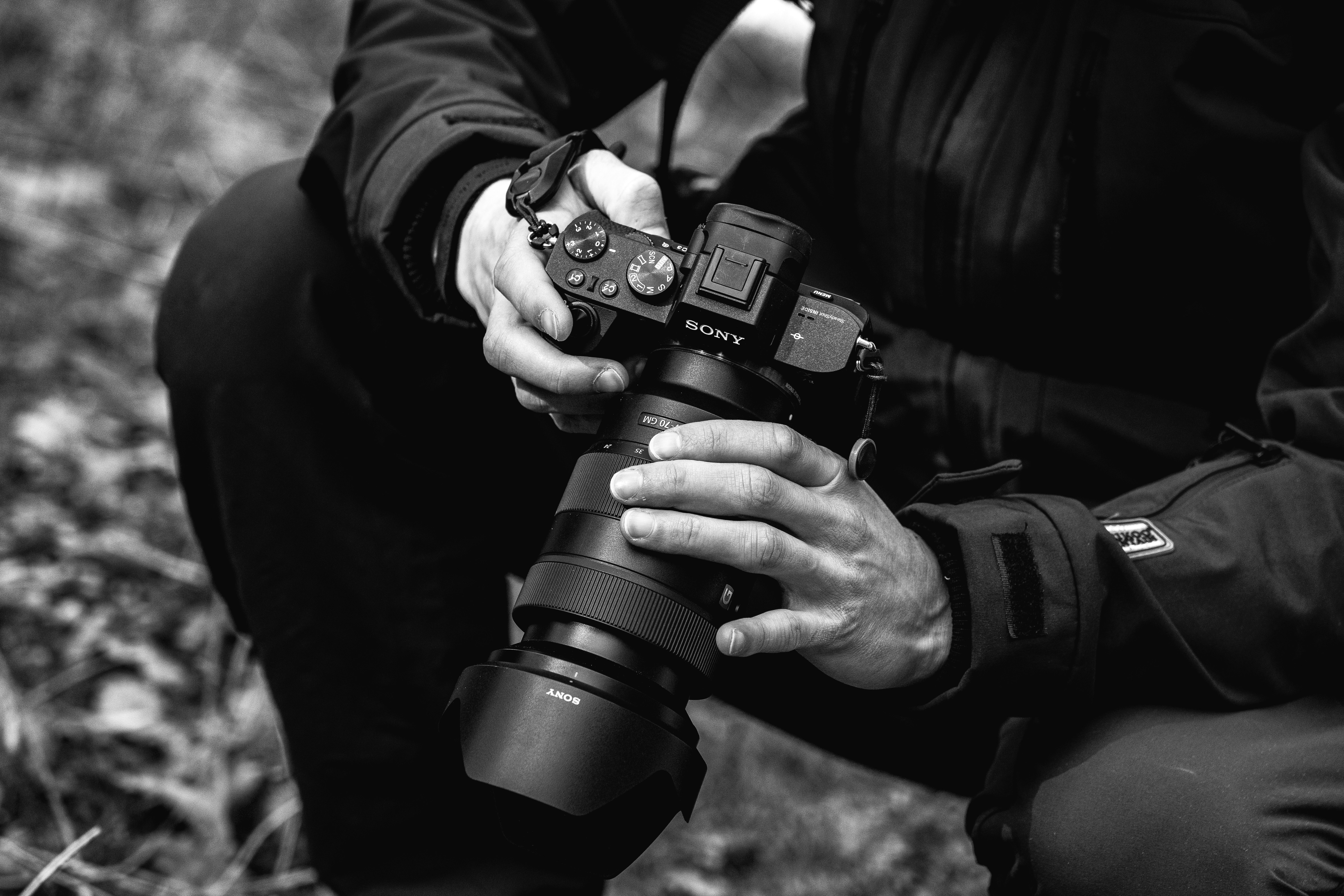 grayscale photo of person holding dslr camera