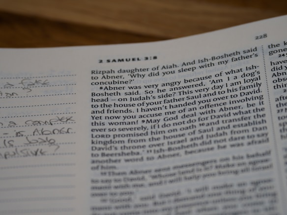 A close-up view of an open book, specifically a page from the Bible. The visible text is from 2 Samuel 3:8. The page is accompanied by a lined section on the left side with handwritten notes in pencil.