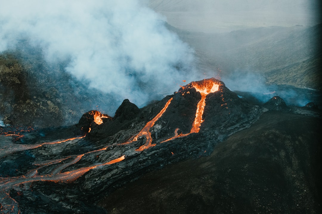 brown and black mountain with white clouds, The erupting volcano in Iceland.