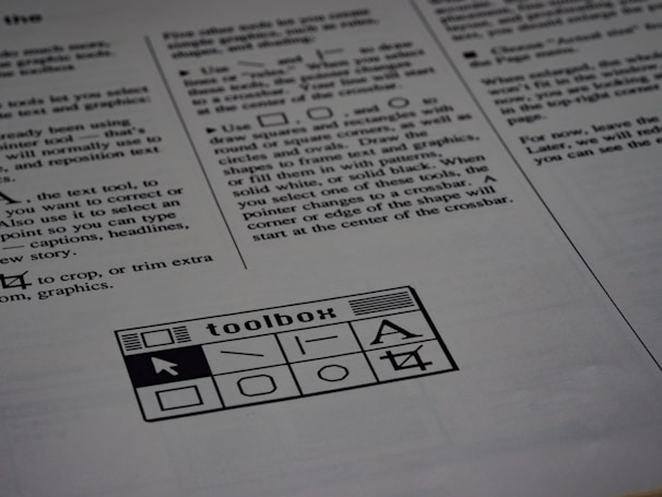 A printed page of text is visible, featuring instructions and explanations related to drawing tools and text editing. In the bottom section of the page, there is a graphic of a toolbox with various tool icons including a text tool and shape tools.