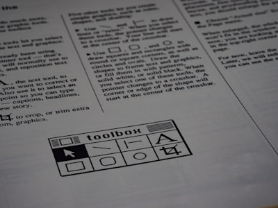 A printed page of text is visible, featuring instructions and explanations related to drawing tools and text editing. In the bottom section of the page, there is a graphic of a toolbox with various tool icons including a text tool and shape tools.