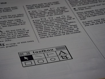 A printed page of text is visible, featuring instructions and explanations related to drawing tools and text editing. In the bottom section of the page, there is a graphic of a toolbox with various tool icons including a text tool and shape tools.