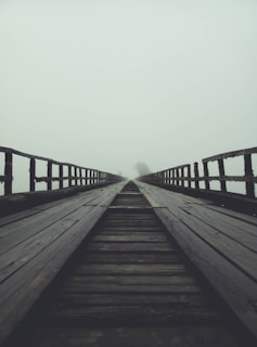 A misty old wooden bridge over a quiet river at Ravens Ferry, with shadows hinting at ghostly figures.