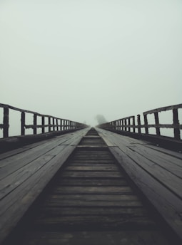 A misty old wooden bridge over a quiet river at Ravens Ferry, with shadows hinting at ghostly figures.