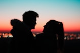 Silhouetted couple against the deep charcoal evening sky, with Jaipur’s historic skyline in the background.