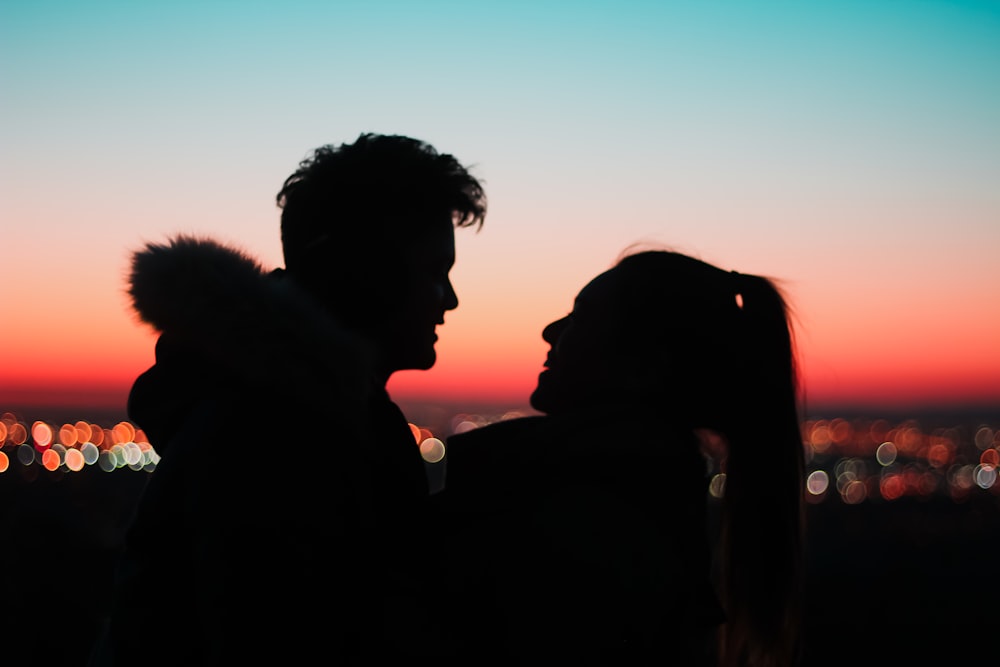 silhouette of man and woman kissing during sunset