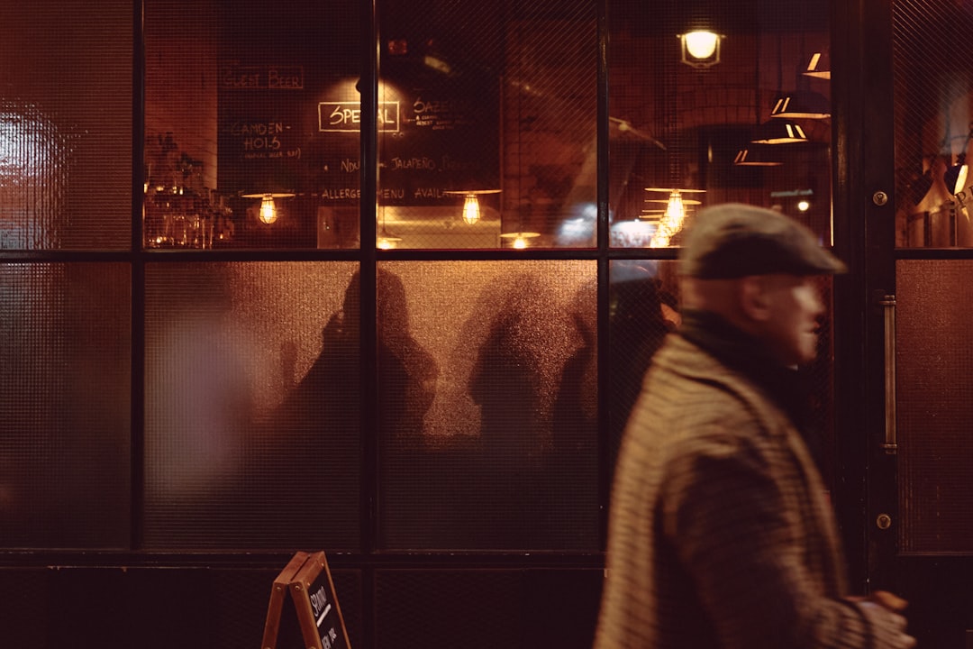 woman in gray jacket standing near glass window