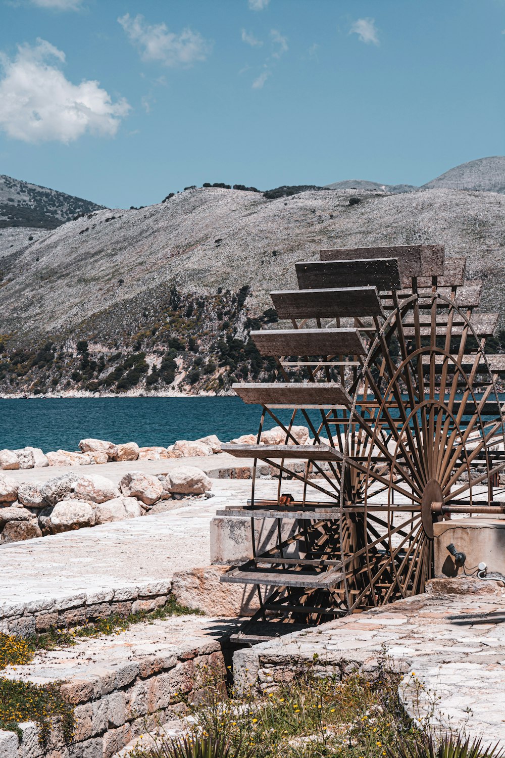 brown wooden stairs on rocky shore near body of water and mountain during daytime