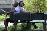 A smiling couple enjoying a sunny park bench together.