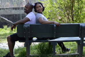 A smiling couple enjoying a sunny park bench together.