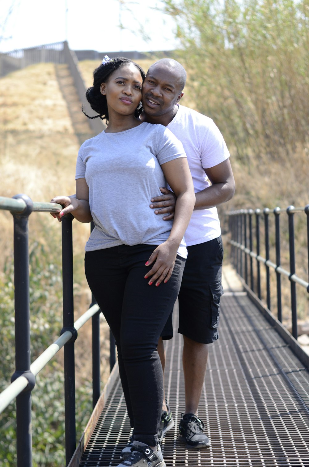 woman in white crew neck t-shirt and black skirt standing on brown wooden bridge during