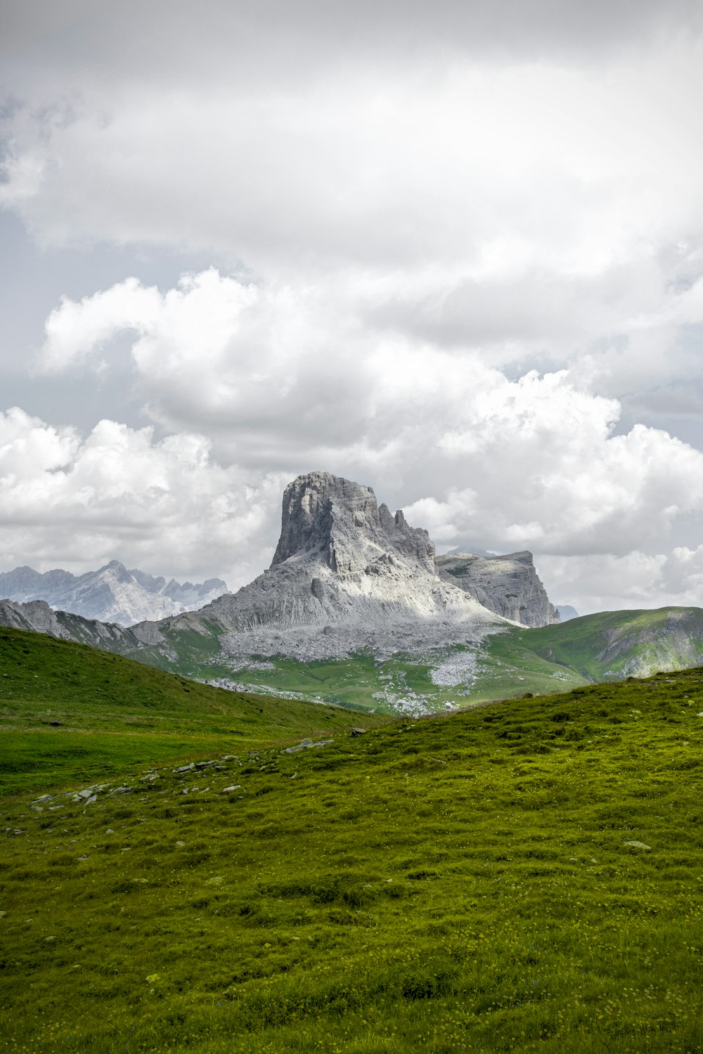 green grass field near snow covered mountain under white clouds during daytime