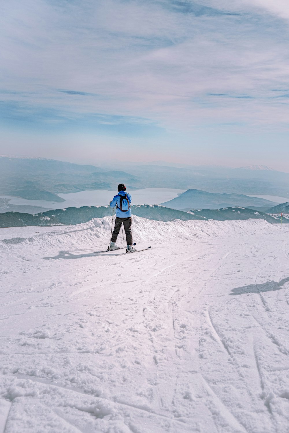 person in red jacket and blue denim jeans standing on snow covered ground during daytime