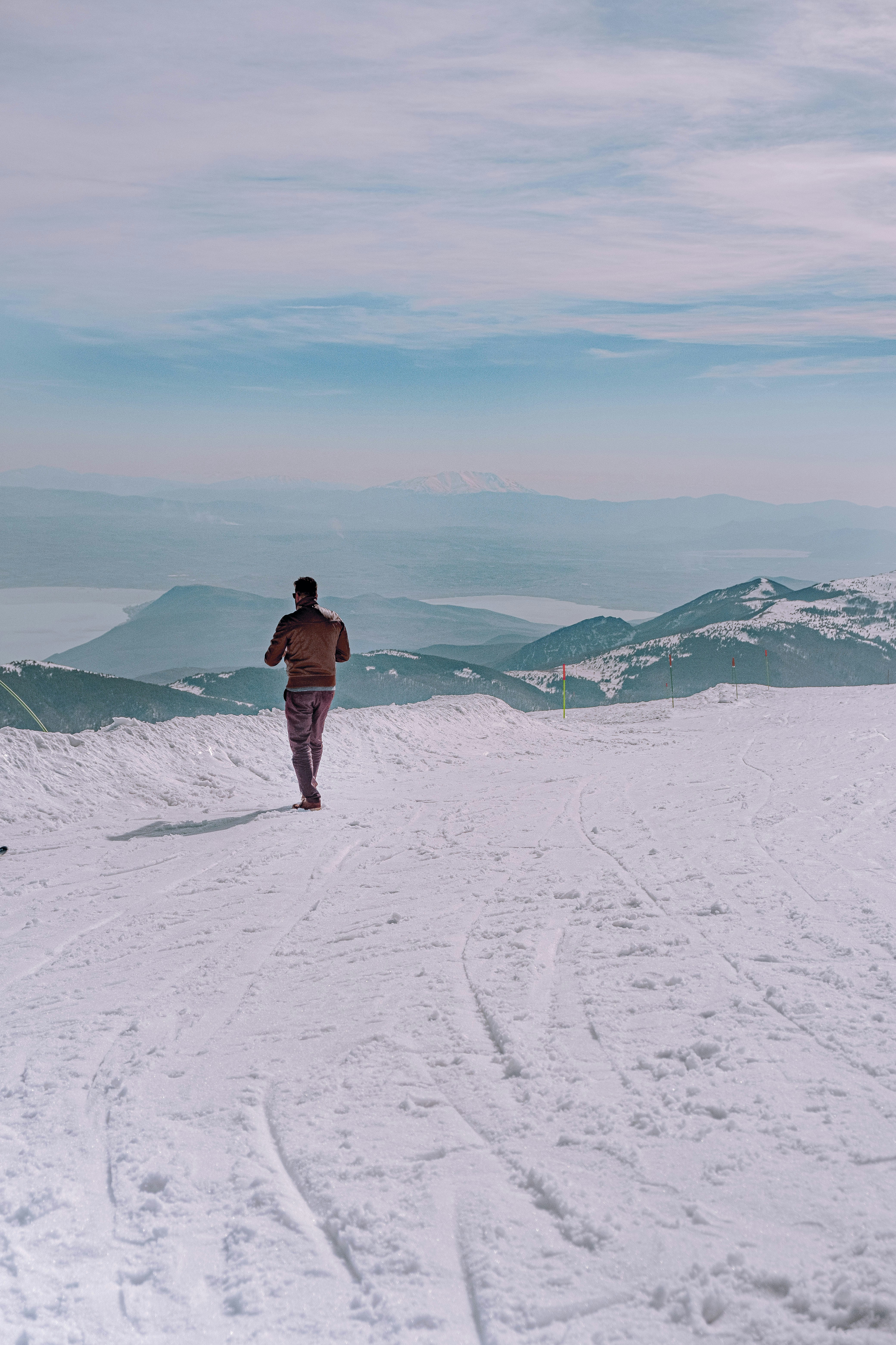 man in brown jacket standing on snow covered ground during daytime