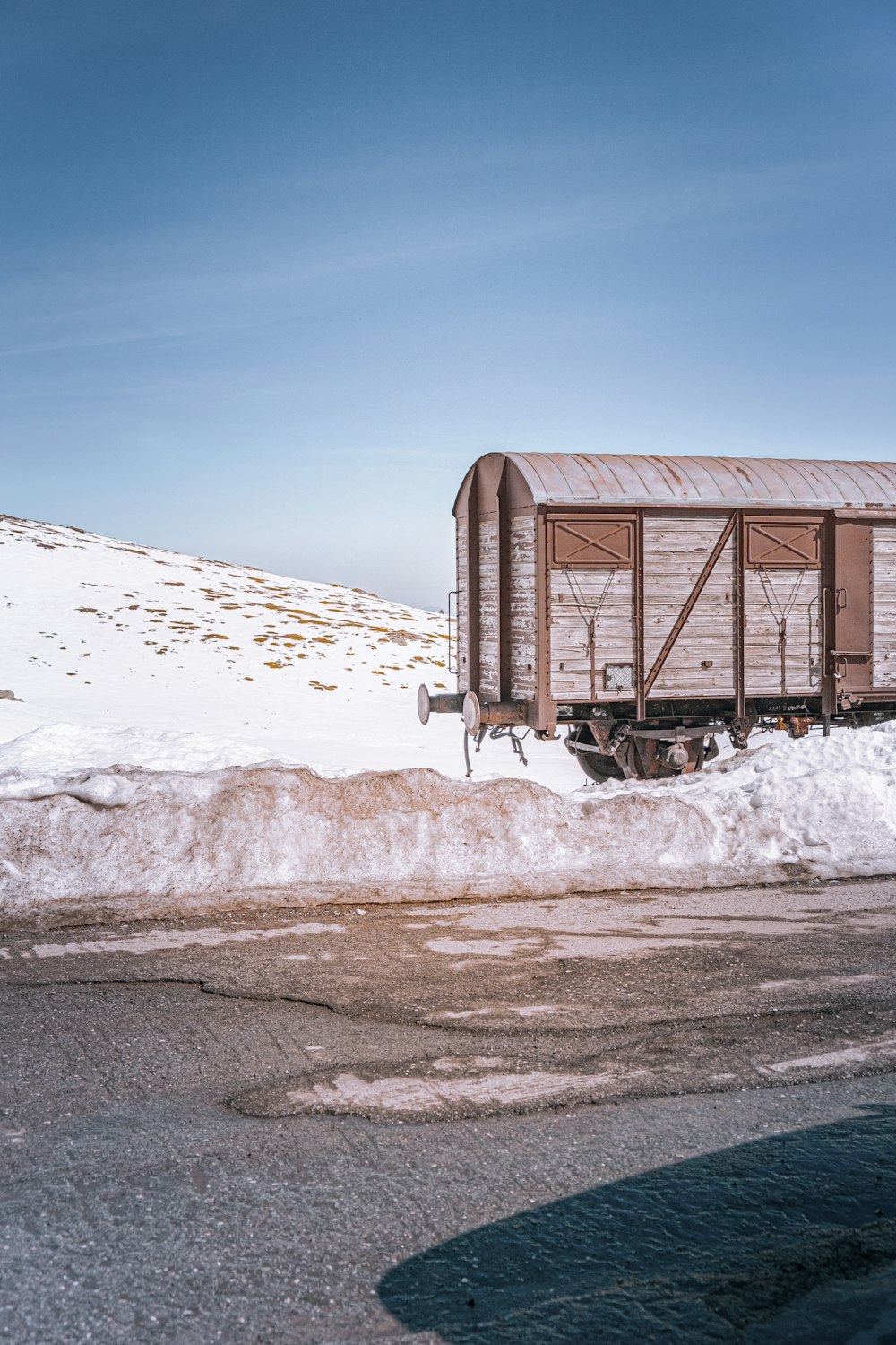 brown wooden house on snow covered ground under blue sky during daytime