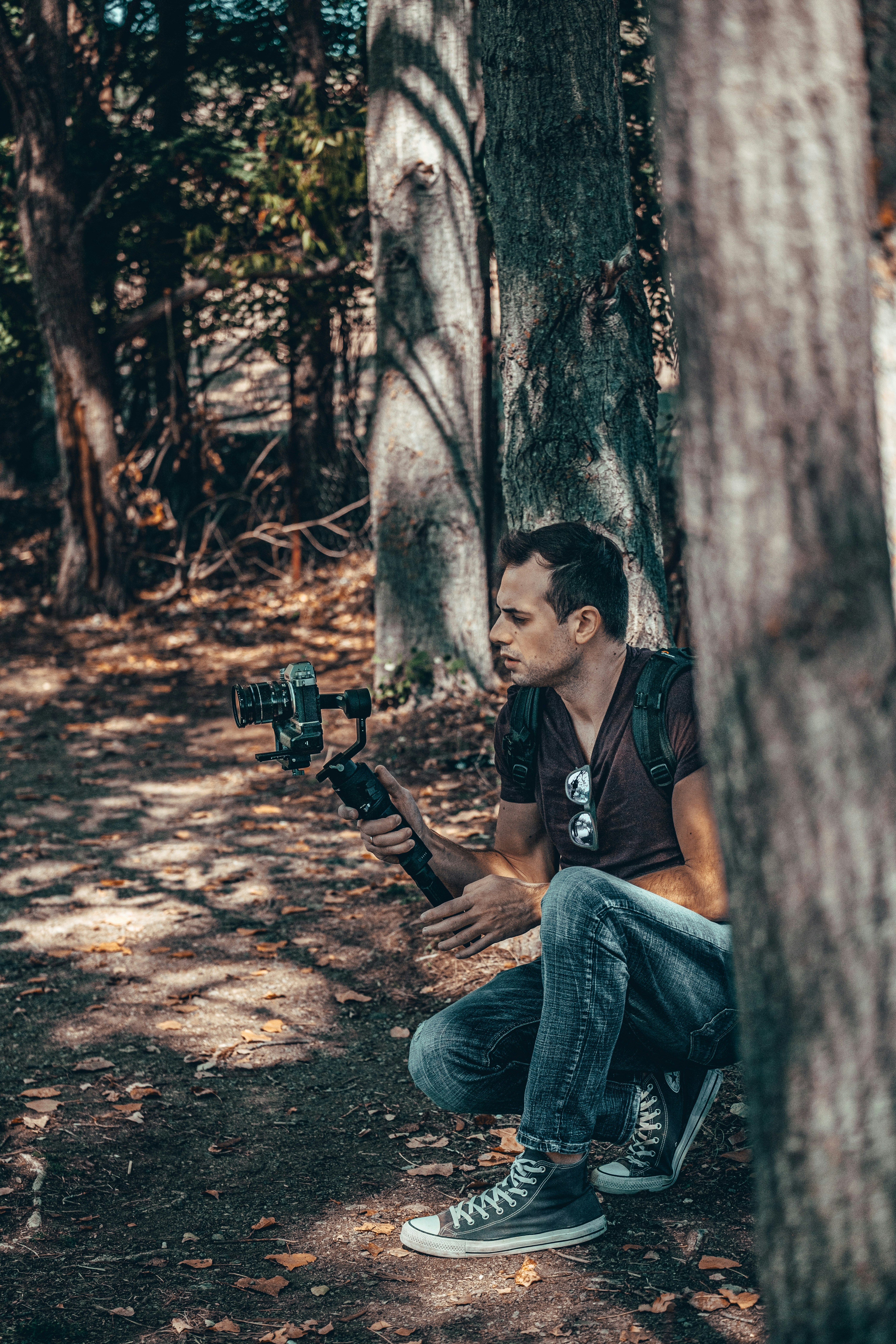 man in black jacket and blue denim jeans holding black dslr camera