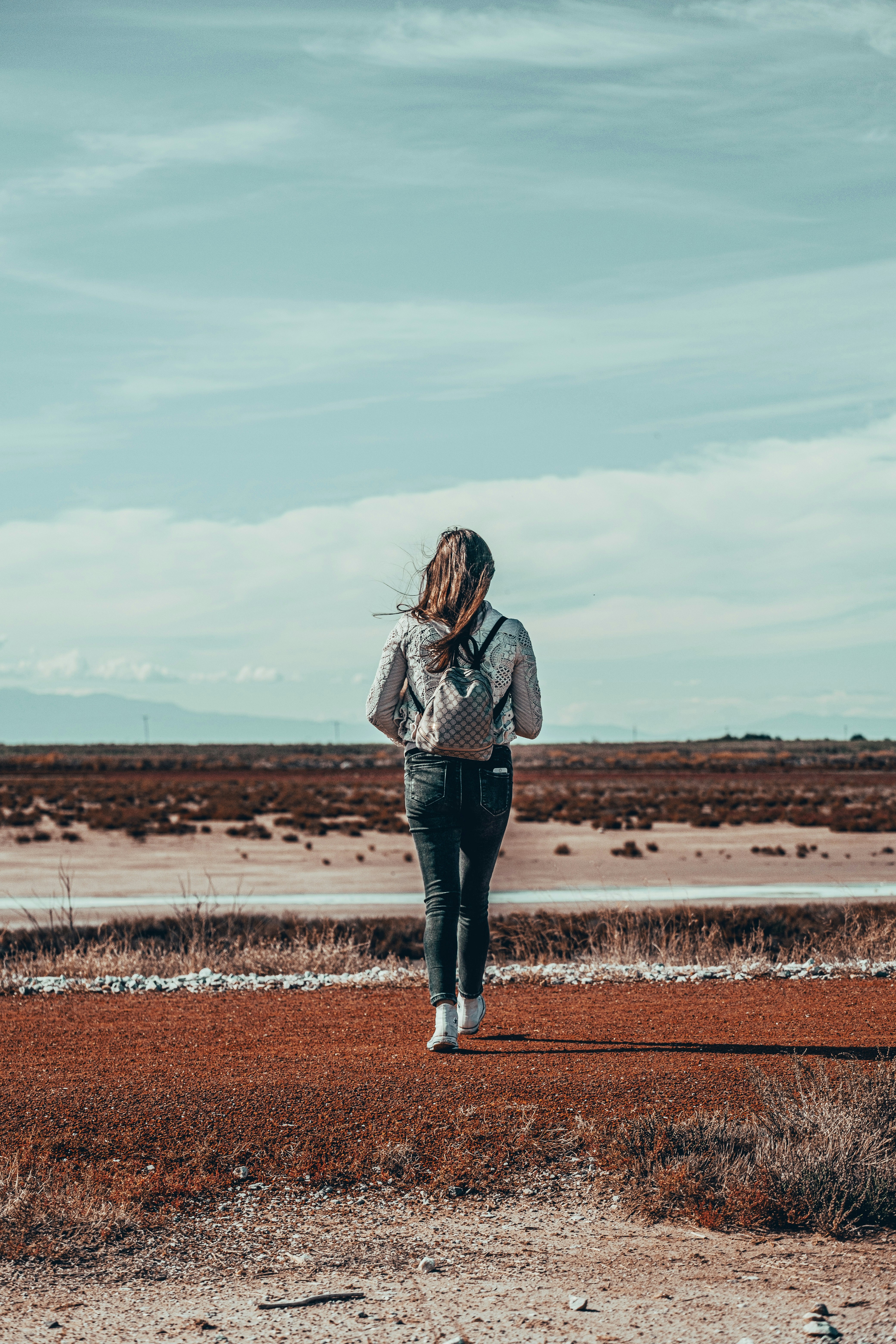 woman in brown and white plaid long sleeve shirt standing on brown field during daytime