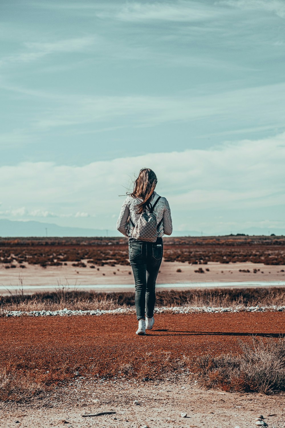 woman in brown and white plaid long sleeve shirt standing on brown field during daytime