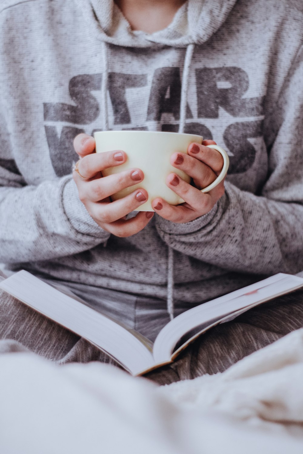 person in gray zip up jacket holding white ceramic mug