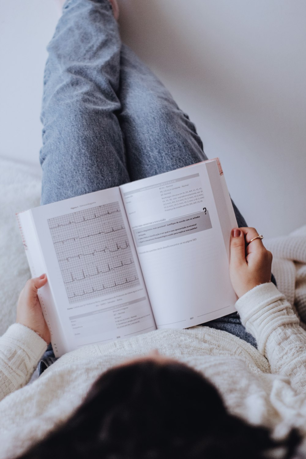 person in gray sweater holding book