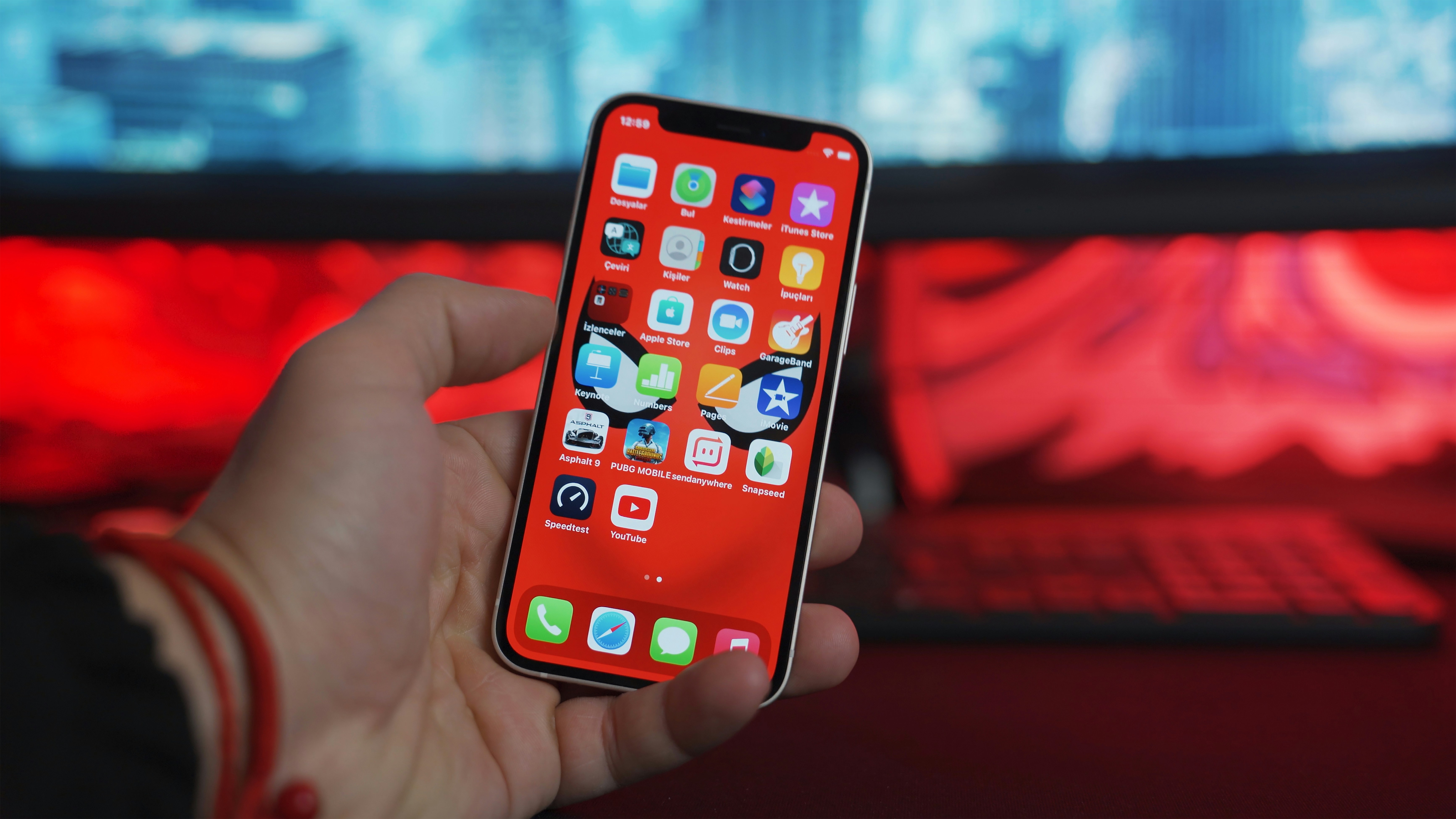 Hand holding iPhone 12 mini on colorful background