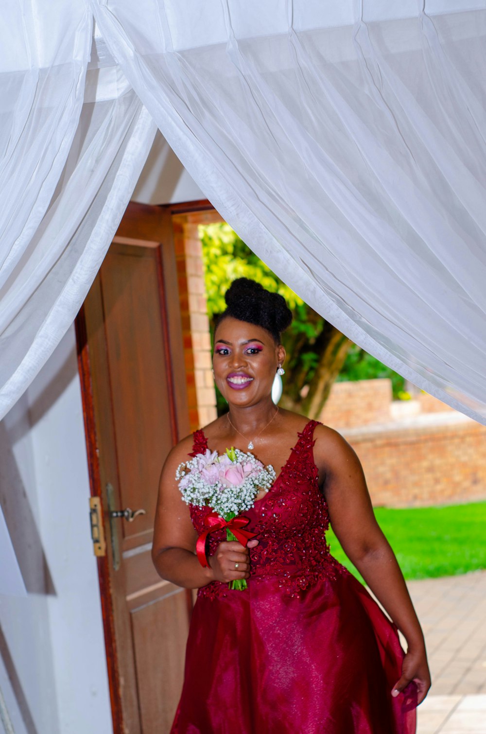 woman in red tube dress holding bouquet of flowers