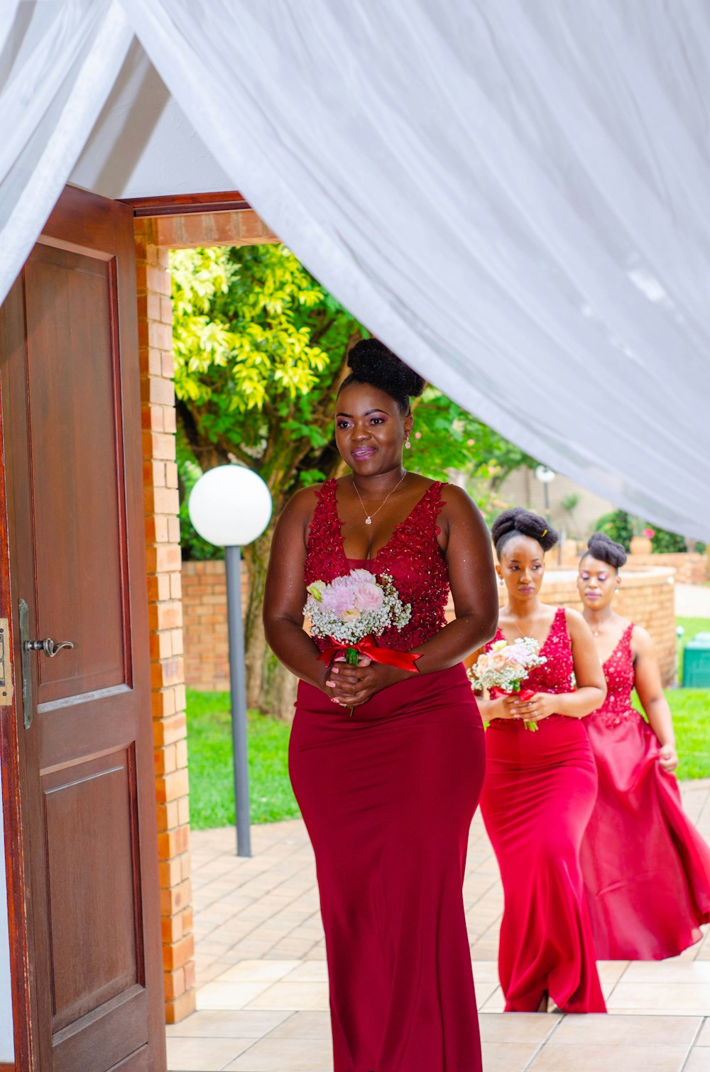 woman in red tube dress standing beside woman in white wedding dress