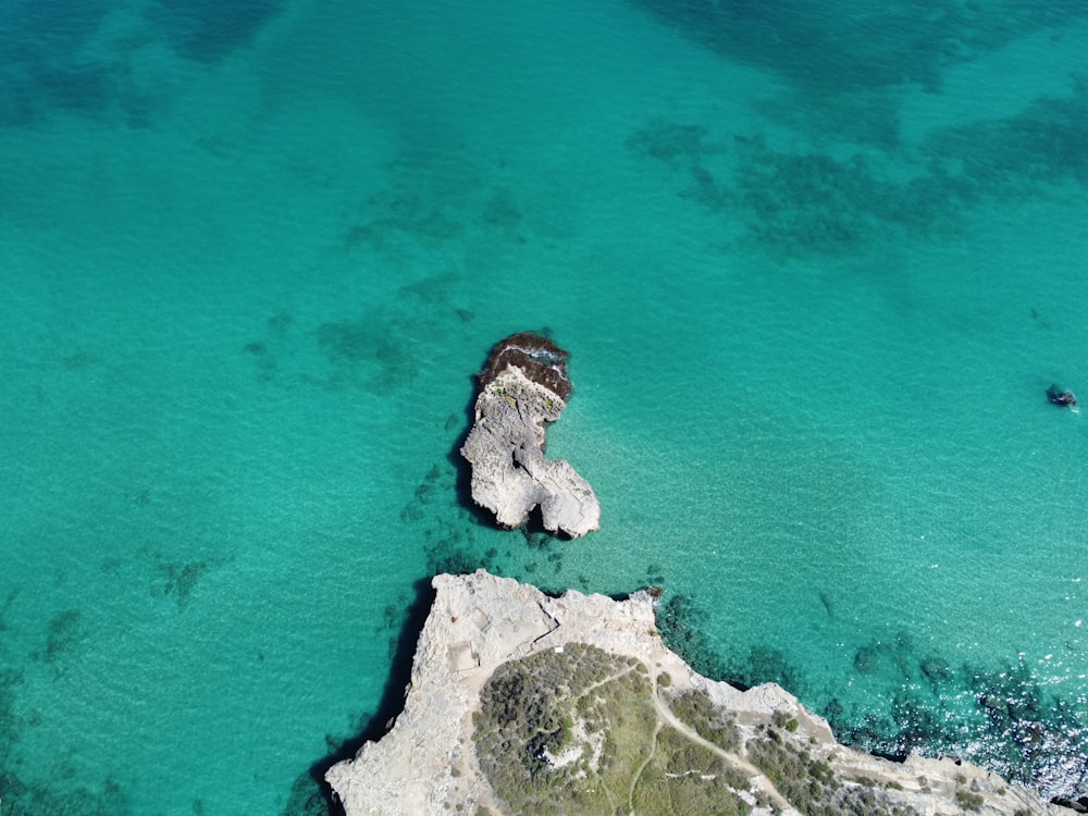aerial view of white and brown rock formation on blue sea during daytime