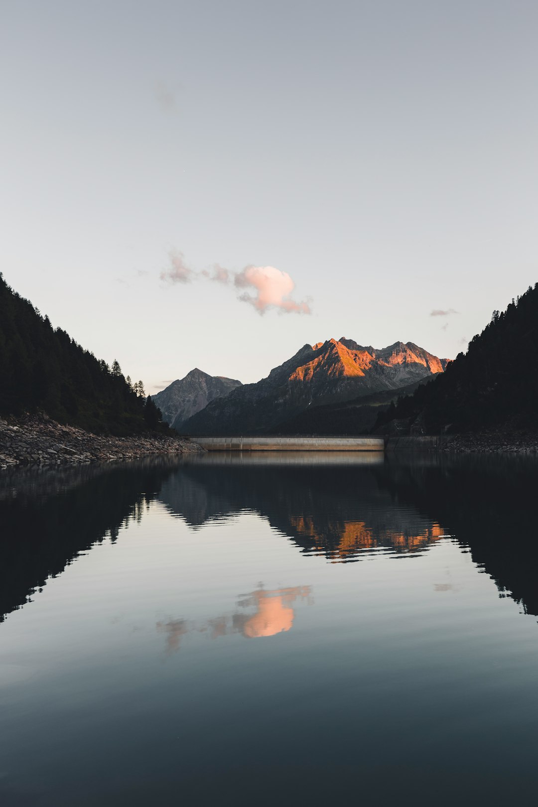 lake near mountain under cloudy sky during daytime