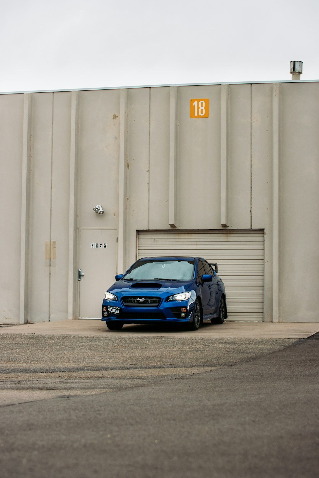 blue car parked beside white wall