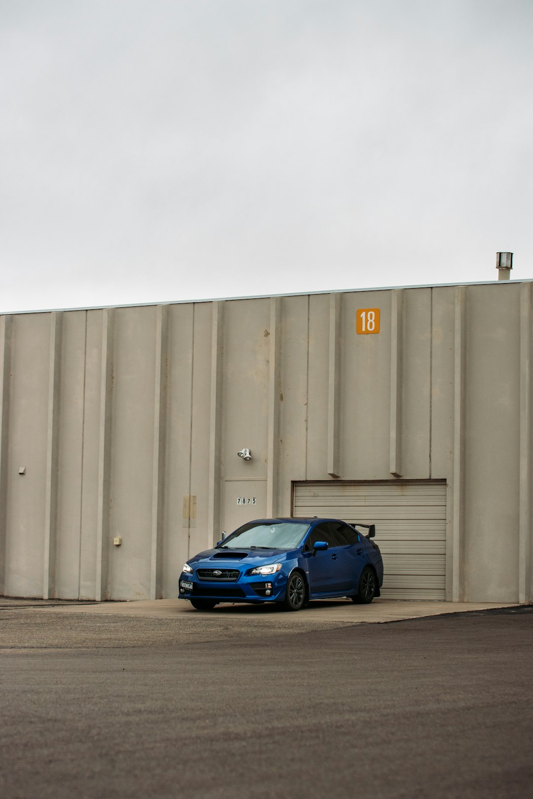 blue sedan parked beside gray wall