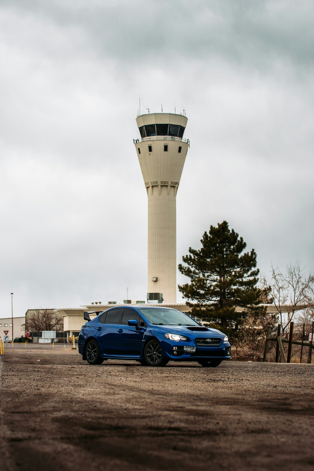 blue sedan parked beside white tower