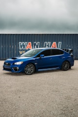 A sleek car being carefully loaded onto a shipping container at a busy port.