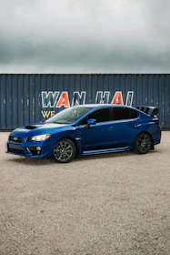 A sleek Japanese sports car being loaded onto a shipping container at a busy port.