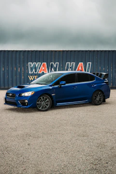 A sleek car being unloaded from a shipping container at a busy port.