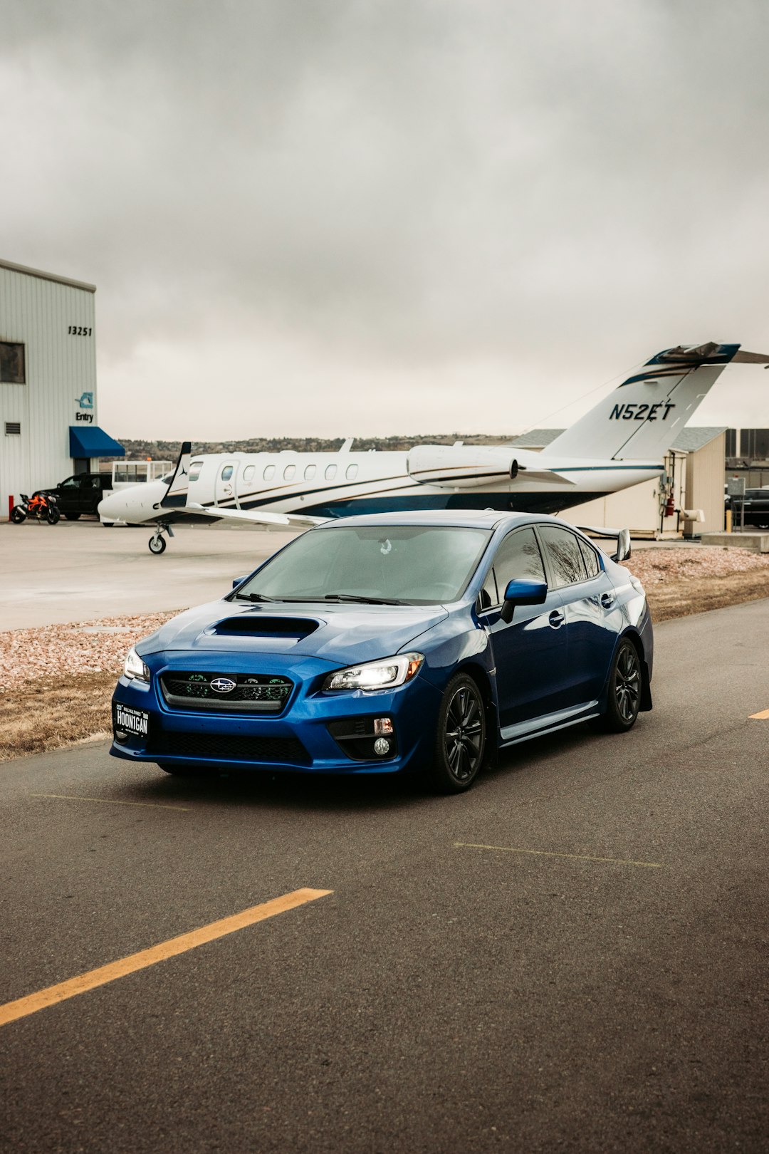 blue honda car parked near white airplane