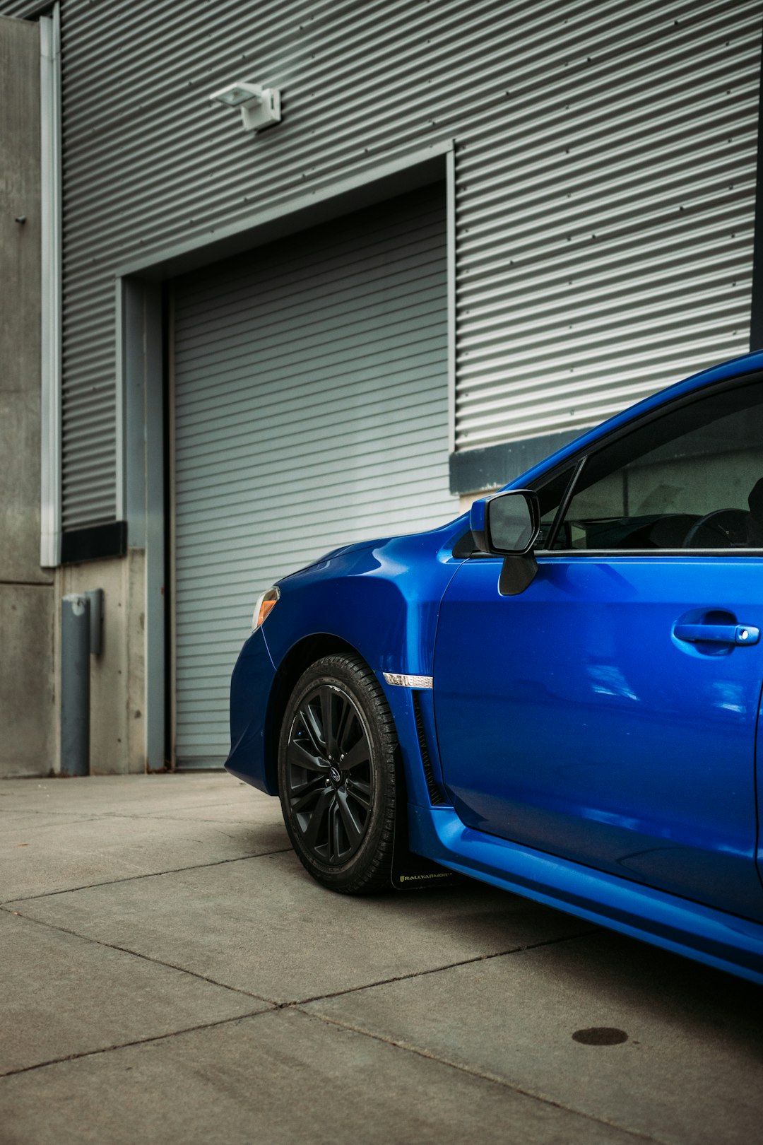 blue car parked near white garage door